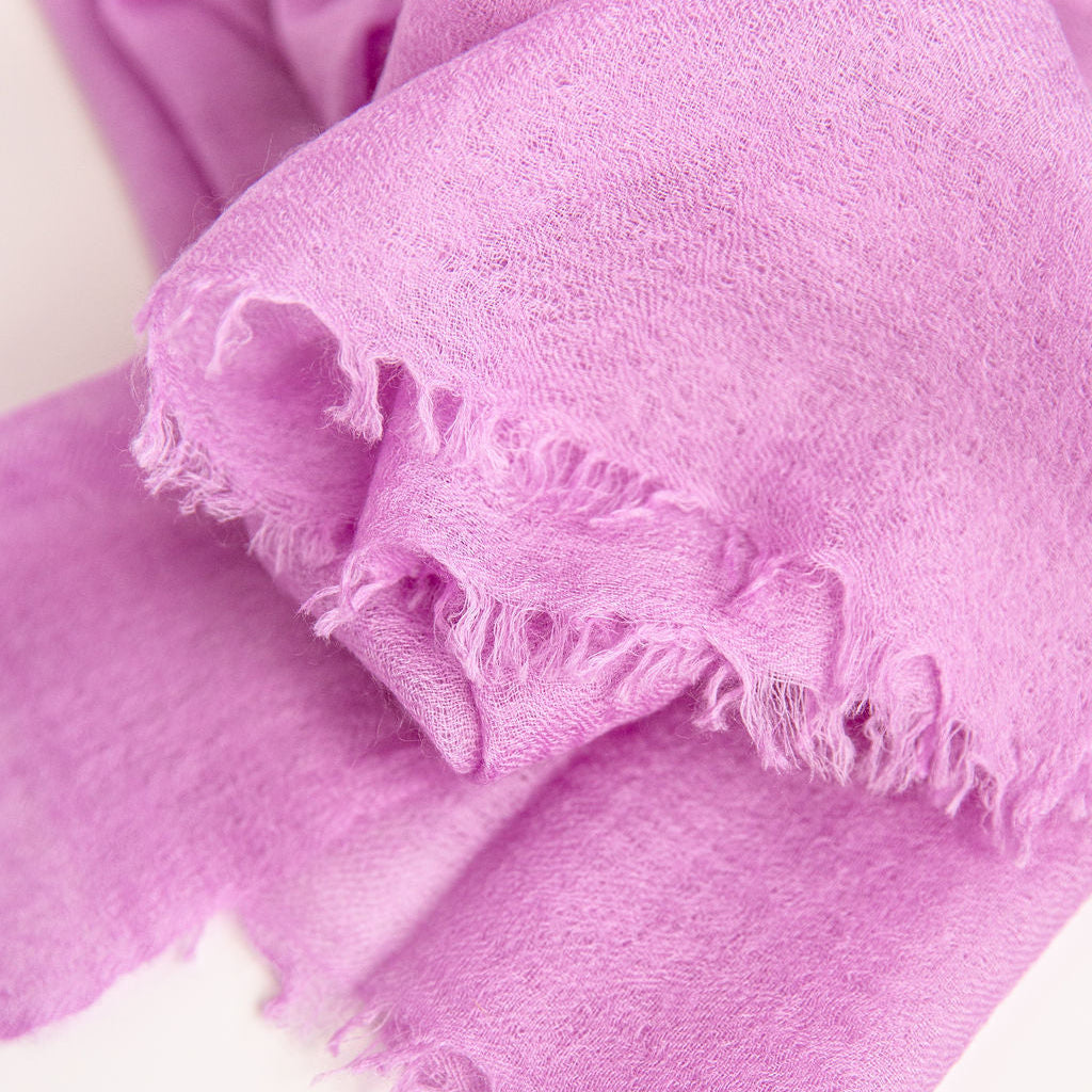 Close-up of a pink fabric with frayed edges on a white background