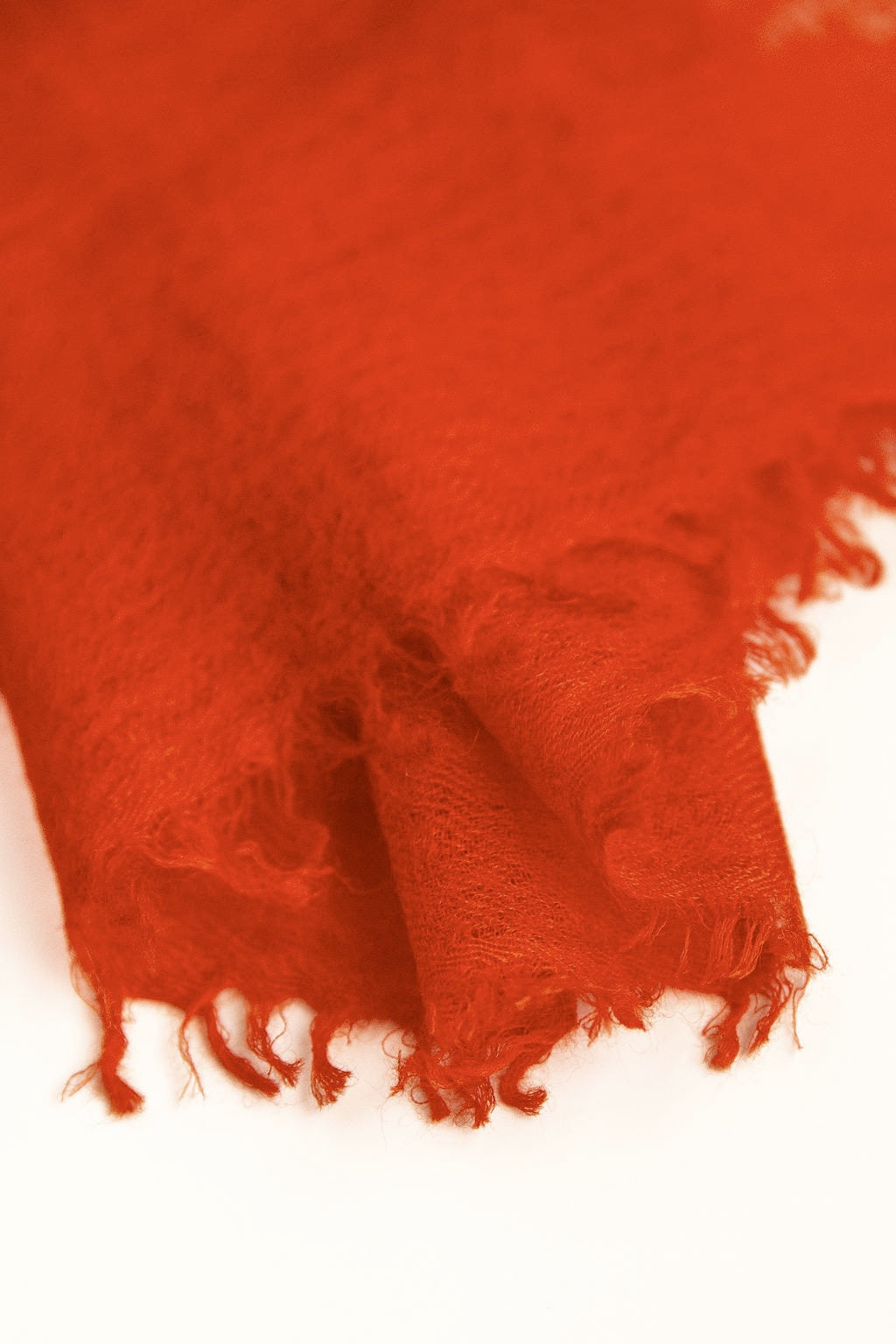 Close-up of a red fabric with frayed edges on a white background