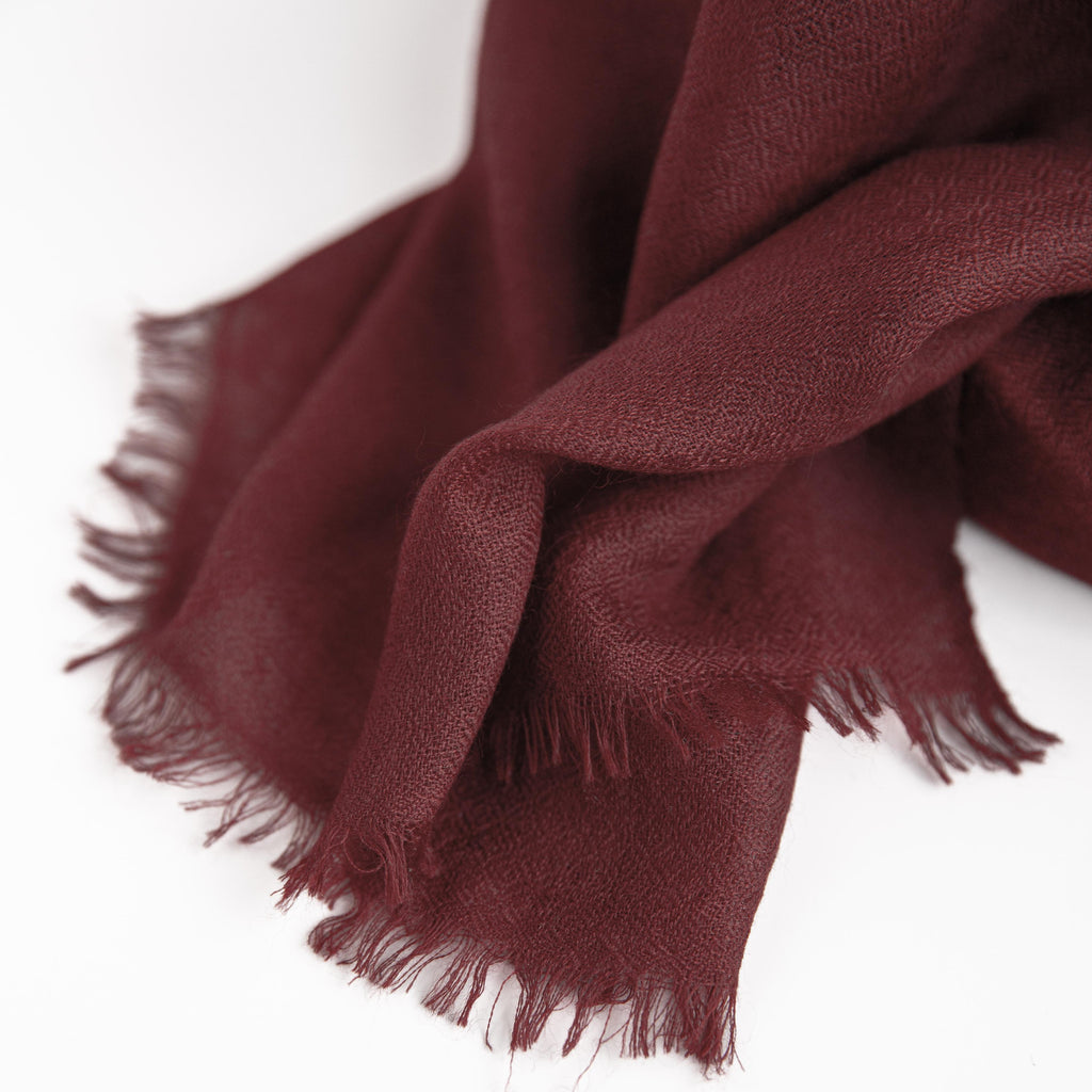Burgundy scarf with frayed edges on a white background