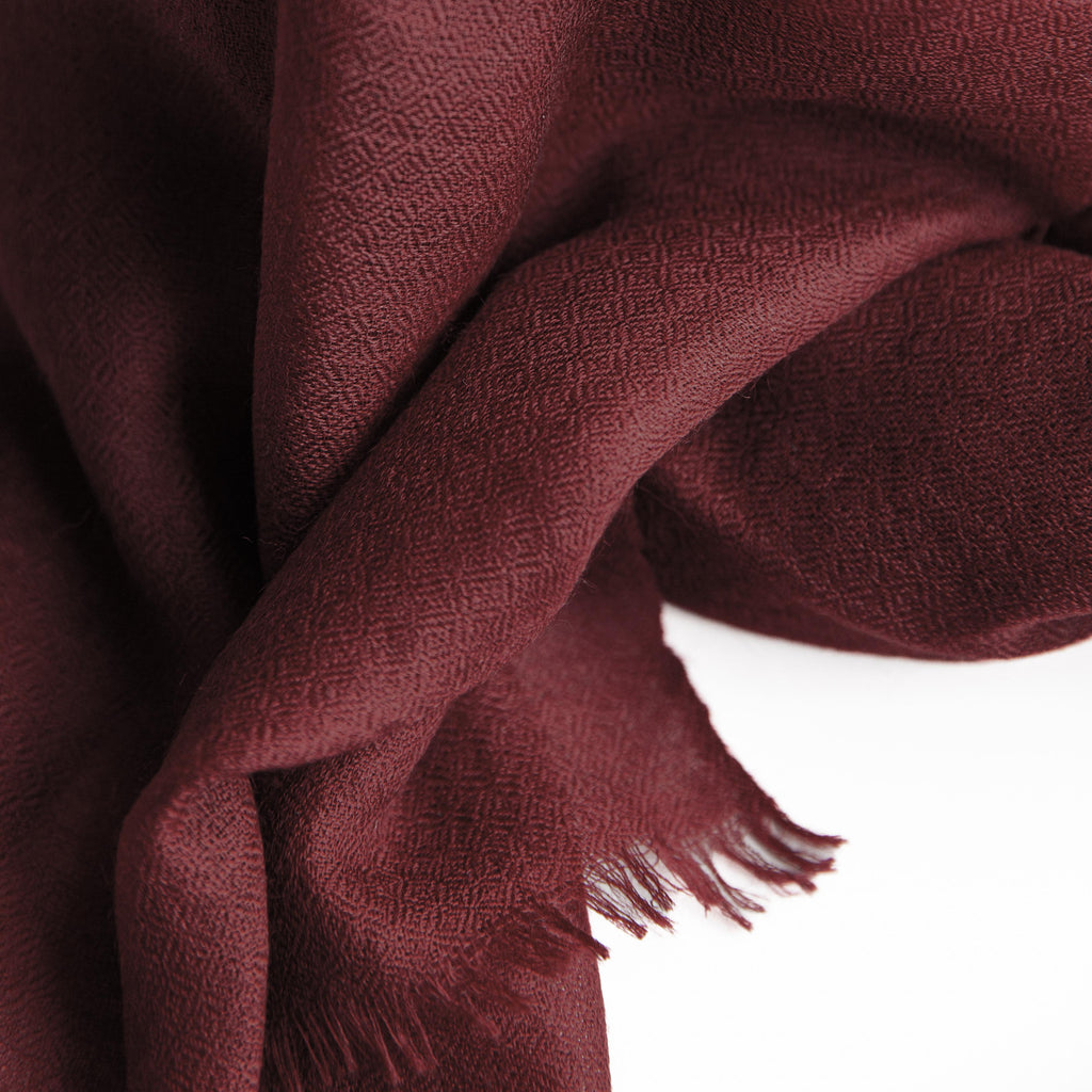 Close-up of a burgundy scarf with frayed edges on a white background